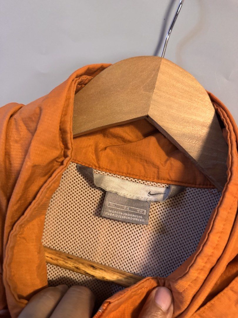 Nike Orange Half-Zip Hooded Windbreaker Jacket (Category: Coats, Jackets and Outerwear) located in Alaminos. Submitted by outfitcheck.ph (Listing ID 1469102125, Image 3). Description: - Brand: Nike - Size: 2XL - Color: Bright orange with white piping details - Features: Half-zip, hood, mesh lining, and adjustable drawstring hem - Pockets: Front flap pocket with dark button closure - Branding: Embroidered Nike swoosh on the left sleeve - Origin: M