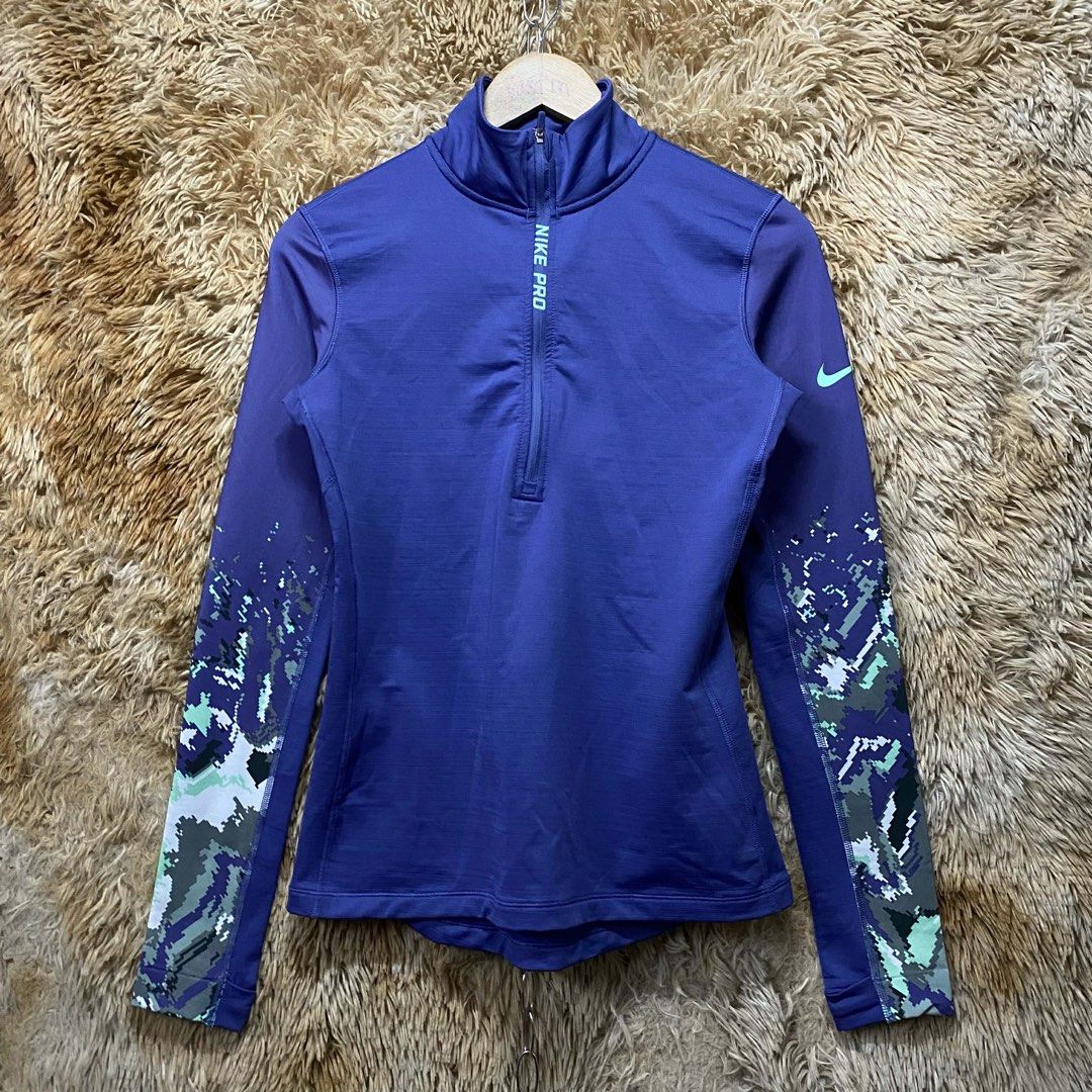 Nike Pro Purple Half-Zip Long Sleeve Workout Top (Category: Activewear) located in Butuan. Submitted by jc13thrifts (Listing ID 1469064230, Image 1). Description: - Brand: Nike Pro - Style: Half-zip long sleeve top with mock neck - Color: Purple with mint green logo and vertical front branding - Details: Pixelated camo pattern on forearms (green, grey, purple, white) - Ideal for: Running, gym workouts, and sporty casual outfits.