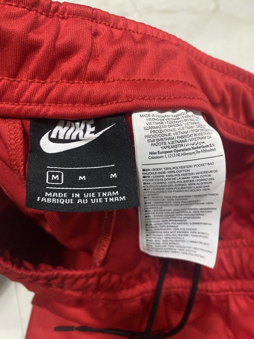 Nike Red Track Pants Repeat Tape Size M (Category: Joggers) located in Manila. Submitted by japhetcond32104 (Listing ID 1469111046, Image 3). Description: - Brand: Nike - Color: Bright red with black side taping - Features: Multiple white swoosh logos down each leg, embroidered red Nike logo near pocket, drawstring elastic waist, and zip ankles - Size: Medium - Material: 100% polyester (Made in Vietnam) - Condition: Clean inside and out.