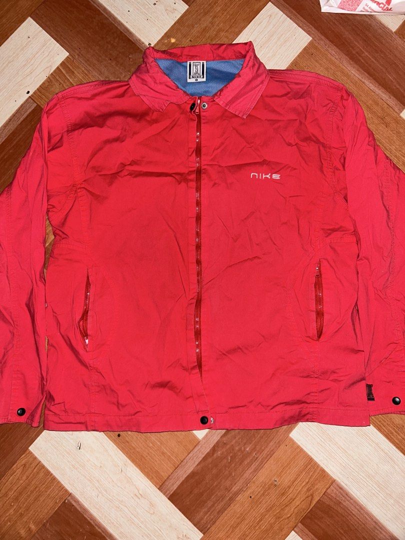 Nike Red Vintage Jacket Full Zip Windbreaker (Category: Coats, Jackets and Outerwear) located in Manila. Submitted by yoshi_shin (Listing ID 1469149637, Image 1). Description: - Color: Vibrant red with contrasting light blue inner lining - Closure: Full front zipper with button fasteners at hem and cuffs - Pockets: Two secure zippered side pockets - Branding: Small white embroidered Nike logo on upper left chest - Back: Clean solid red back panel