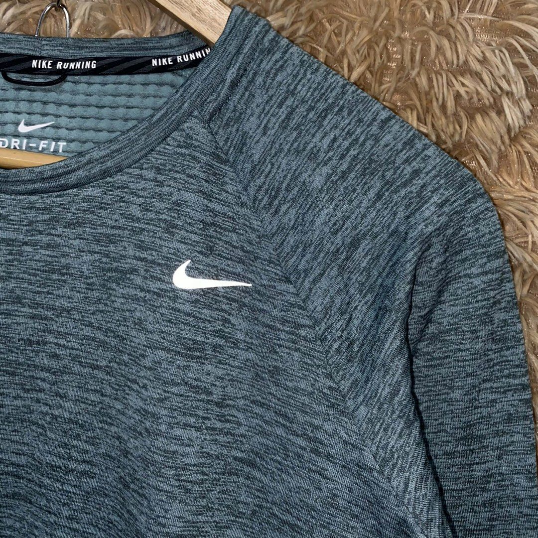 Nike Running Dri-FIT Long Sleeve Gray Pullover (Category: Activewear) located in Butuan. Submitted by jc13thrifts (Listing ID 1469064101, Image 3). Description: - Brand: Nike - Material: Dri-FIT moisture-wicking fabric - Design: All-over textured knit pattern with reflective Nike swoosh logo - Features: Convenient small side zipper pocket near the hem for keys/cards and thumbholes at the cuffs - Condition: Excellent, ready for your runs and gym s