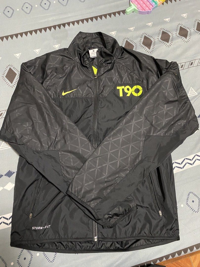 Nike T90 Storm-Fit Black Jacket Size M (Category: Coats, Jackets and Outerwear) located in Taguig. Submitted by maaarrrrrcky (Listing ID 1469012976, Image 1). Description: - Brand: Nike T90 - Color: Black with bright yellow accents and neon green inner lining - Size: Medium - Material: 100% polyester (Made in China) - Weather Tech: Nike Storm-Fit protection - Design: Geometric pattern on shoulders and sleeves - Features: Full zip closure and secu