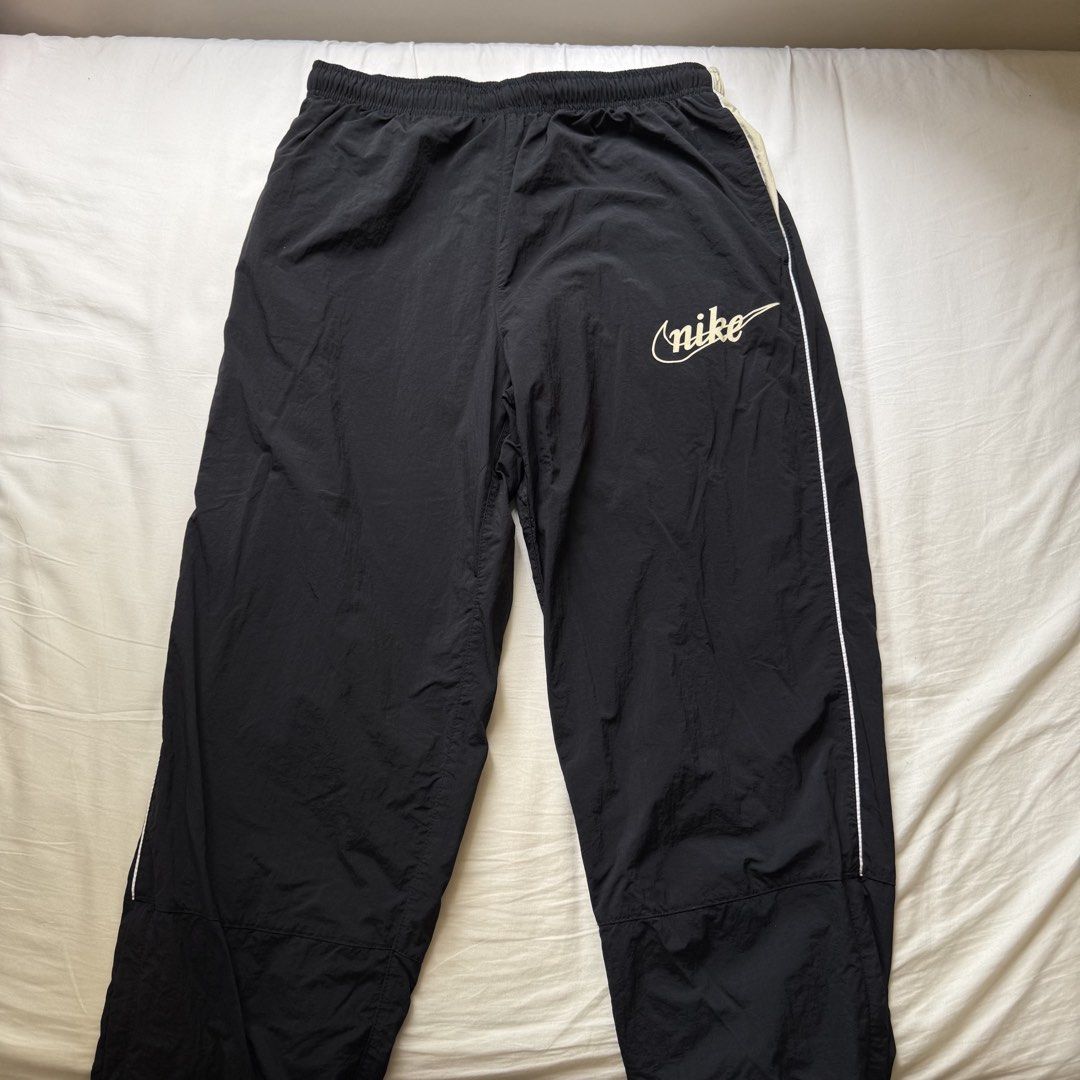 Nike Vintage Style Script Logo Nylon Track Pants Black Large (Category: Joggers) located in Pasig City. Submitted by notshynotmeee (Listing ID 1468957514, Image 1). Description: - Brand: Nike - Color: Black with cream and white side piping - Size: Large - Material: Durable nylon outer with breathable mesh lining - Design: Retro cursive Nike script logo on left thigh - Features: Elastic waistband with adjustable drawstring and zippered ankle cuffs