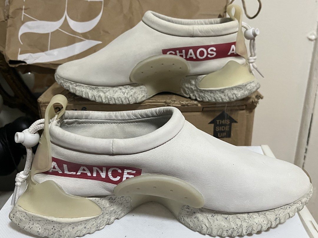 Nike x Undercover Jun Takahashi Moc Flow Light Bone (Category: Sneakers) located in Manila. Submitted by chococoffeeboy (Listing ID 1468969618, Image 2). Description: -Nike x Undercover Jun Takahashi Collaboration “Chaos & Balance” -Very hard to find! -Fresh pair! - Clean off-white leather suede upper - Signature 'CHAOS' and 'BALANCE' red text branding - Features: Speckled midsole, translucent heel clips, and back toggle lace system - Comfort: Sl