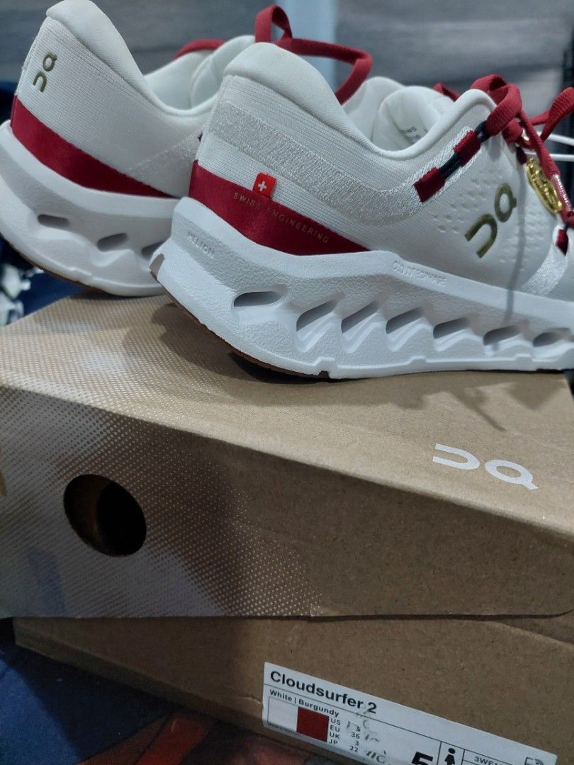 On Cloudsurfer 2 White Burgundy Sneakers (Category: Sneakers) located in San Antonio. Submitted by cleverstar_cb8bf4 (Listing ID 1469085406, Image 3). Description: - Brand: On Cloudsurfer 2 - Colorway: White and burgundy with red laces and gum rubber outsole panels - Size: US 5 / EU 36 - Condition: Brand new, never worn, fresh in box - Inclusions: Original box, tags, and a special gold coin charm attached to the laces - Features: Swiss engineerin