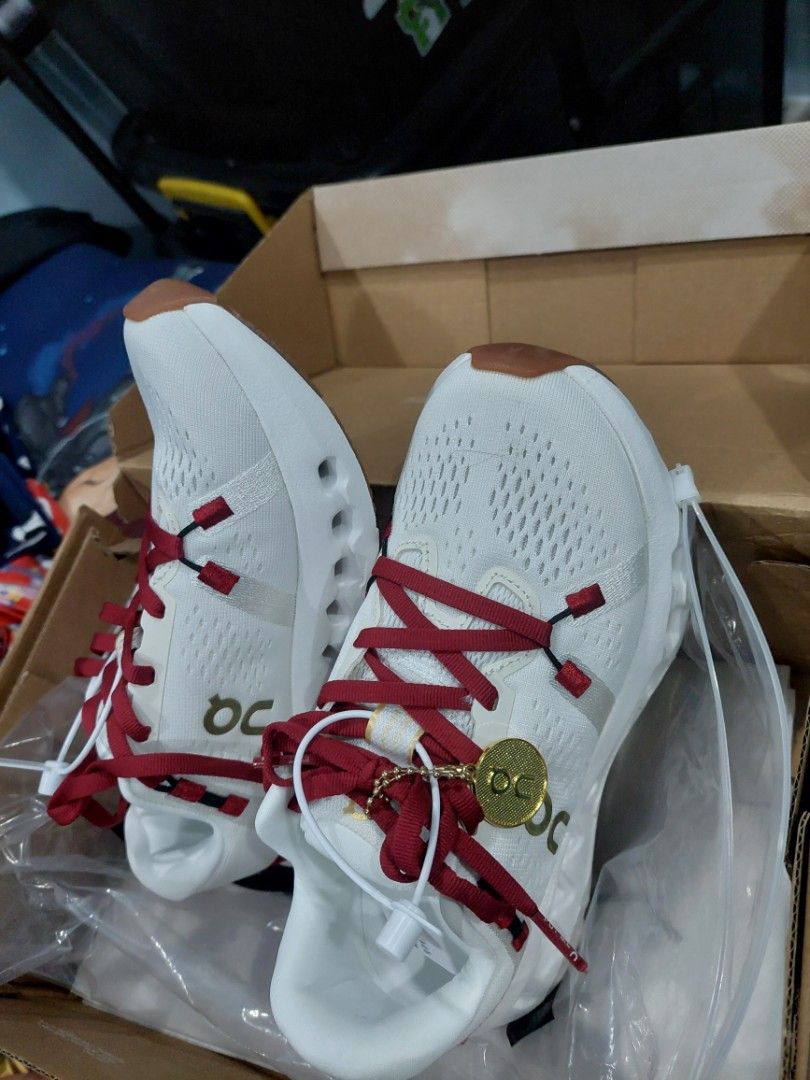 On Cloudsurfer 2 White Burgundy Sneakers (Category: Sneakers) located in San Antonio. Submitted by cleverstar_cb8bf4 (Listing ID 1469085406, Image 1). Description: - Brand: On Cloudsurfer 2 - Colorway: White and burgundy with red laces and gum rubber outsole panels - Size: US 5 / EU 36 - Condition: Brand new, never worn, fresh in box - Inclusions: Original box, tags, and a special gold coin charm attached to the laces - Features: Swiss engineerin