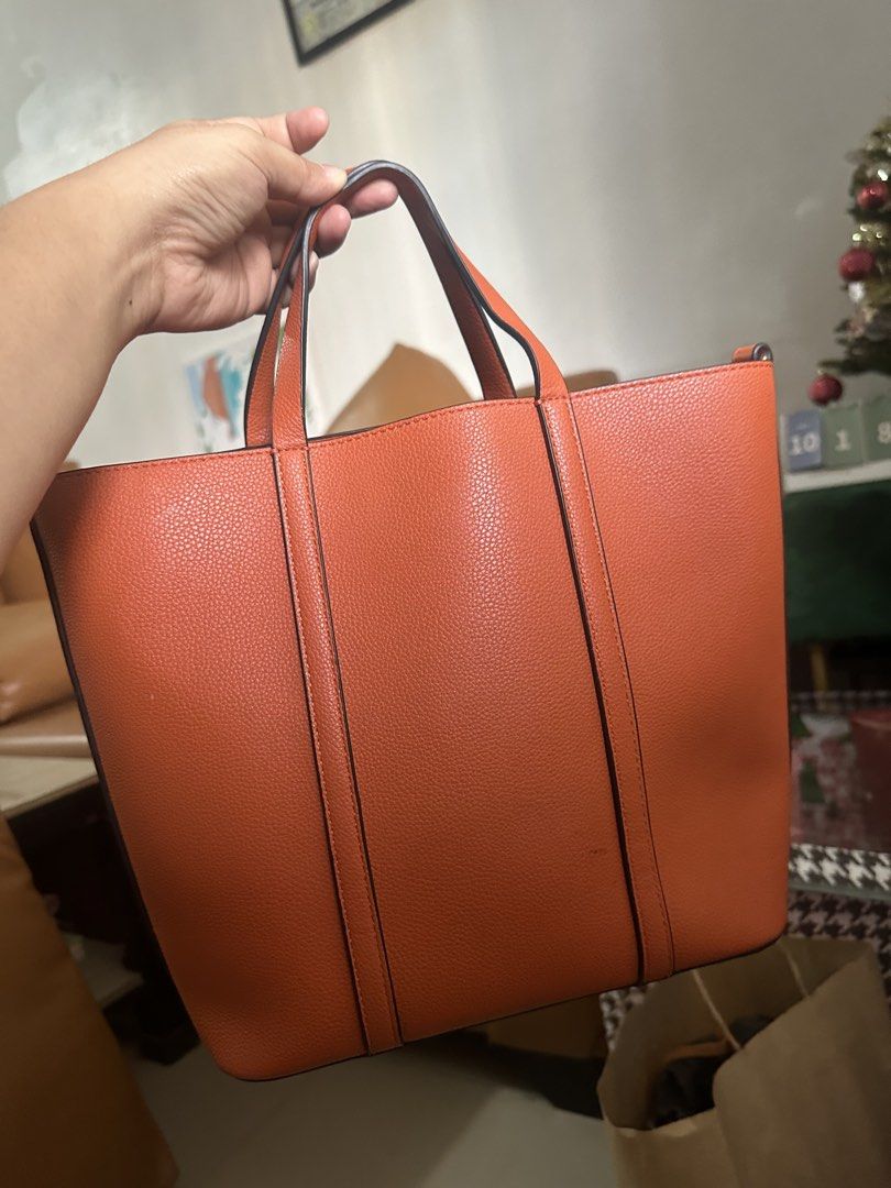 Orange Leather Tote Bag with Shoulder Strap (Category: Tote Bags) located in Manila. Submitted by jaamvs (Listing ID 1468957483, Image 1). Description: - Material: Premium orange textured leather - Carrying options: Dual top handles and a removable shoulder strap - Closure & Interior: Zippered main compartment with clean off-white fabric lining - Hardware: Silver-tone accents on strap attachments - Capacity: Structured shape with plenty of space 