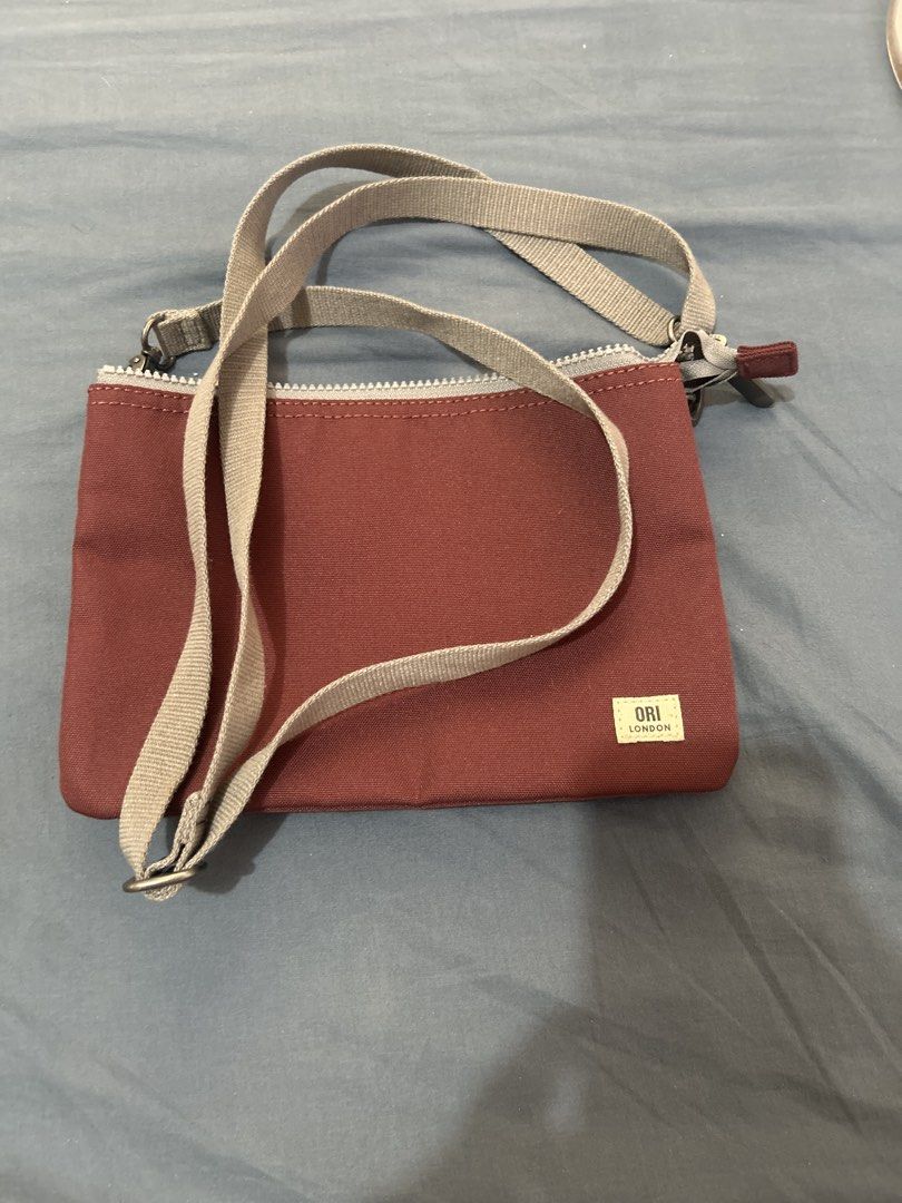 ORI London Multi-Compartment Crossbody Bag (Category: Cross-body Bags) located in Las Pinas. Submitted by mollysan1 (Listing ID 1468933874, Image 1). Description: - Brand: ORI London - Color: Maroon canvas with an adjustable grey strap - Storage: Multiple zipped compartments and slip pockets for phone, keys, and cards - Condition: Clean interior lining and smooth-running zippers - Ideal for: Daily errands, casual outings, and travel - MOP: GCash 