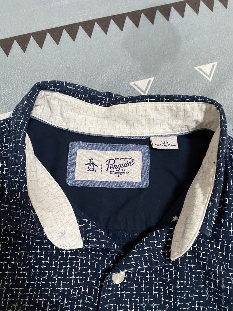 Original Penguin Short Sleeve Button Down Shirt Size L (Category: Tshirts & Polo Shirts ) located in Taguig. Submitted by maaarrrrrcky (Listing ID 1469015467, Image 2). Description: - Brand: Original Penguin by Munsingwear - Size: L - Color: Navy blue with white geometric abstract pattern - Material: 100% breathable cotton - Features: Short sleeves, button-down collar, front button closure, and single chest pocket with iconic embroidered penguin 