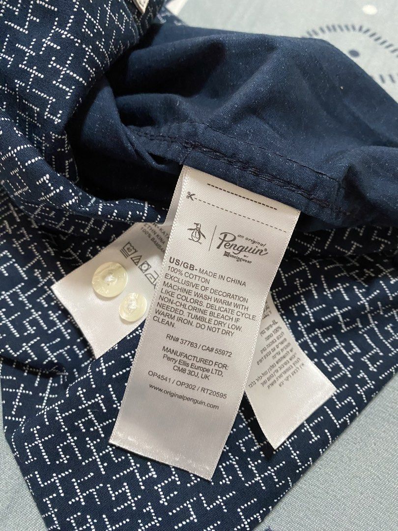 Original Penguin Short Sleeve Button Down Shirt Size L (Category: Tshirts & Polo Shirts ) located in Taguig. Submitted by maaarrrrrcky (Listing ID 1469015467, Image 3). Description: - Brand: Original Penguin by Munsingwear - Size: L - Color: Navy blue with white geometric abstract pattern - Material: 100% breathable cotton - Features: Short sleeves, button-down collar, front button closure, and single chest pocket with iconic embroidered penguin 