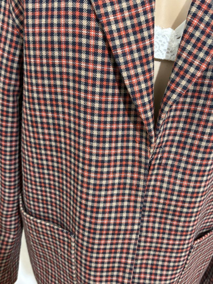Plaid Blazer Jacket Double Lining (Category: Coats, Jackets and Outerwear) located in Cainta. Submitted by tokadore (Listing ID 1468978205, Image 2). Description: - Plaid blazer with red, black, and beige check pattern - Classic tailored fit with a chic buttonless front design - Features structured lapels, front patch pockets, and a chest pocket - Accented with the iconic enamel triangle logo badge - Excellent layering piece for transitional weat