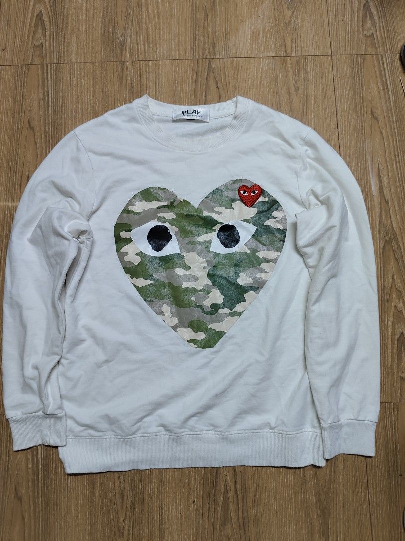 Play Comme des Garcons Camo Heart Wool Sweater (Category: Longsleeves) located in Tacloban City. Submitted by soniaahom51096 (Listing ID 1468960920, Image 1). Description: - Brand: Play Comme des Garcons - Color: White - Material: 100% Wool (Made in Japan) - Design: Large camouflage heart print with iconic embroidered red heart - Style: Classic crewneck pullover - Details: Model OR-T013, AD2017 season - Care: Hand wash only.