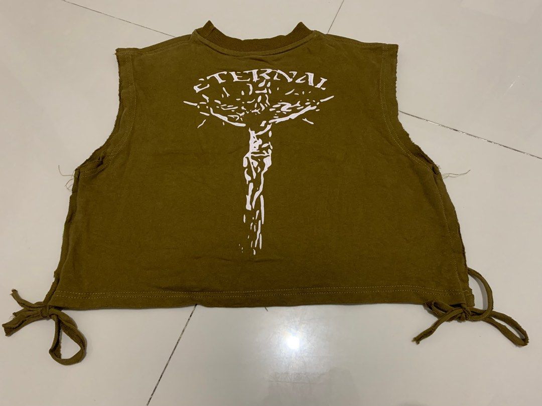 Pleasures Olive Green Crop Top with Graphics (Category: Shirts) located in Manila. Submitted by mixwearclosetclothingstore (Listing ID 1468951529, Image 2). Description: - Brand: Pleasures - Color: Brown with white graphic text - Style: Sleeveless crop top with ribbed round collar - Details: Distressed raw edges at armholes and tie-side slits at the hem - Material: Soft cotton fabric.