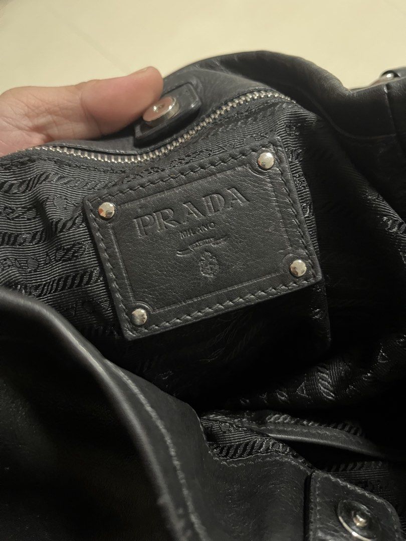 Prada Black Leather Shoulder Bag (Category: Luxury Bags & Wallets) located in Dumangas. Submitted by chiiieeef (Listing ID 1469084176, Image 3). Description: - Authentic black crinkled leather Prada handbag - Stylish silver-tone hardware with top metal logo plaque - Chic decorative side buckle charms - Signature Prada logo fabric interior lining - Interior zippered pocket with authentic leather brand patch - Adjustable double ring shoulder straps