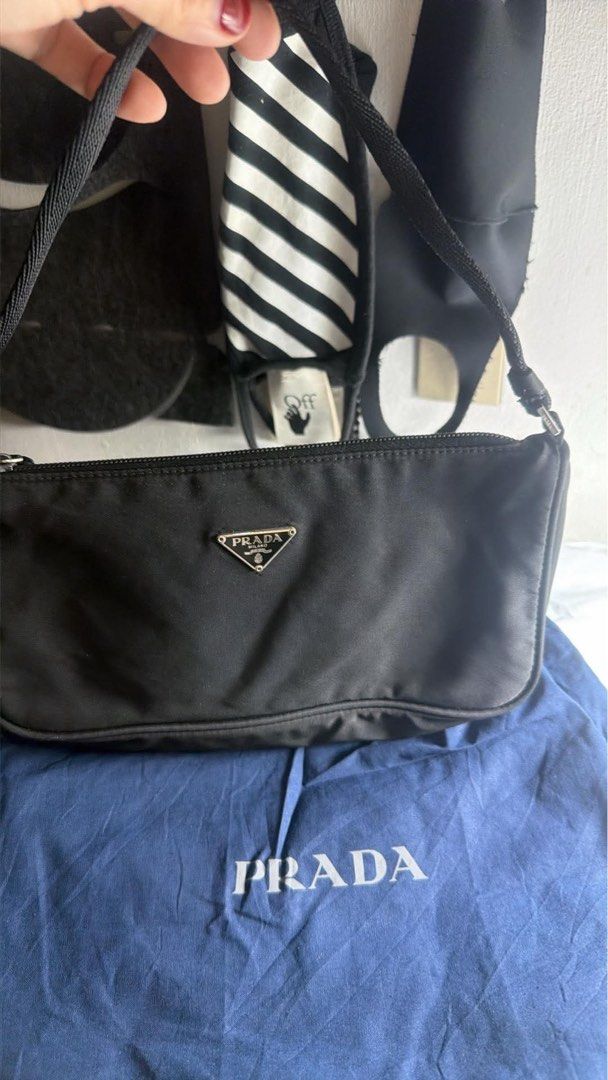 Prada Black Nylon Mini Shoulder Bag (Category: Luxury Bags & Wallets) located in Manila. Submitted by queens_closet_ph (Listing ID 1469003966, Image 2). Description: - Authentic vintage Prada shoulder bag in classic black nylon - Features the iconic triangular metal logo on the front - Secure top zipper closure with a comfortable black strap - Timeless design that easily pairs with any outfit - Includes original blue dust bag and certificate card