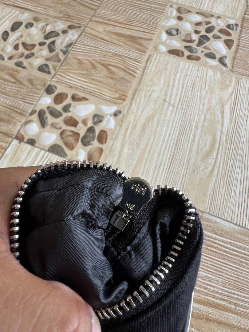 Prada Black Nylon Pouch with Triangle Logo (Category: Luxury Bags & Wallets) located in Iba. Submitted by saploot (Listing ID 1469116444, Image 2). Description: - Authentic Prada black nylon pouch - Iconic enameled metal triangle logo on the front - Smooth and durable riri zipper hardware - Dual strap loops on the back for versatile carrying options - Compact size ideal for coins, cards, keys, or small essentials - Classic, minimalist design suit