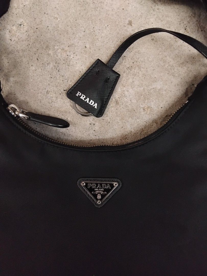 Prada Black Nylon Re-Edition Shoulder Bag (Category: Luxury Bags & Wallets) located in Manila. Submitted by north-thrift (Listing ID 1468947685, Image 2). Description: - Authentic Prada black nylon shoulder bag - Silver-tone hardware with iconic triangle logo plaque - Zip-around closure with leather pull - Includes matching adjustable branded webbed strap - Comes with small detachable pouch featuring key ring - Interior lined with Prada logo jacq