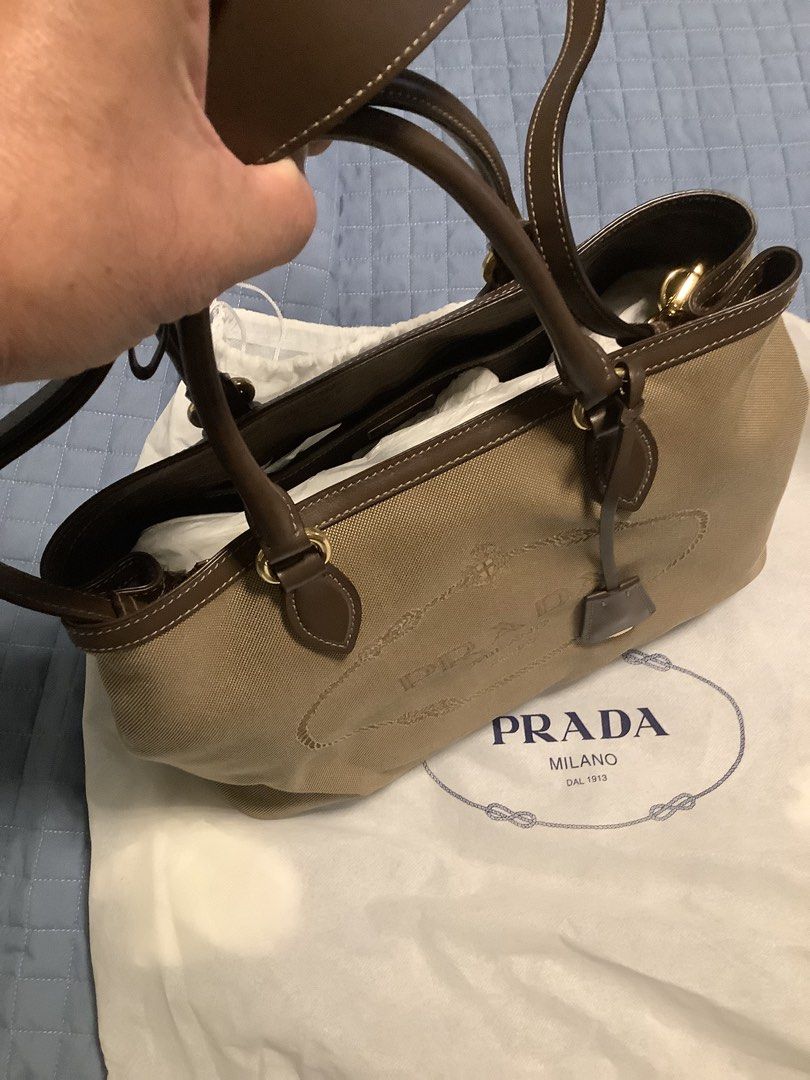 PRADA Borsa A Mano Satchel Bag (Category: Luxury Bags & Wallets) located in Taytay. Submitted by eugeneyoung (Listing ID 1469161056, Image 1). Description: Prada Borsa A Mano Logo Jacquard Satchel. In corda Bruciato. Crossbody bag brown leather. Beige canvas with Brown leather Trim. Gold tone hardware. Snap button closure. One interior slip pocket. Good condition. Authentic Prada bag. .
