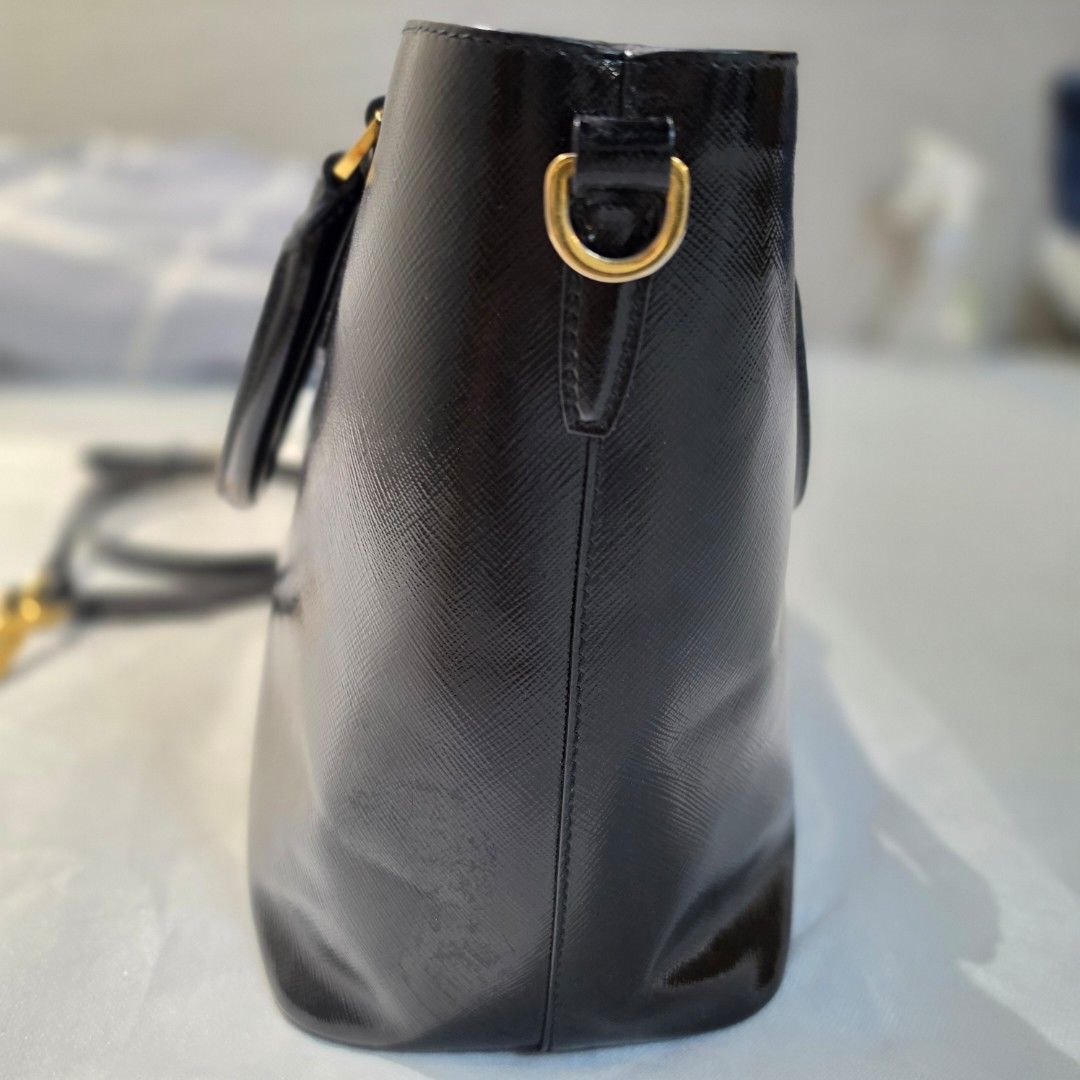 Prada Saffiano Vernice Tote Bag (Category: Luxury Bags & Wallets) located in Paranaque City. Submitted by decluttering_by_anna (Listing ID 1469088091, Image 3). Description: - Authentic Prada tote bag in classic black Saffiano leather - Elegant gold-tone hardware and iconic Prada triangle logo plaque - Dual top handles plus a convenient detachable shoulder strap - Protective metal feet on the bottom base to prevent scuffs - Clean, spacious interi