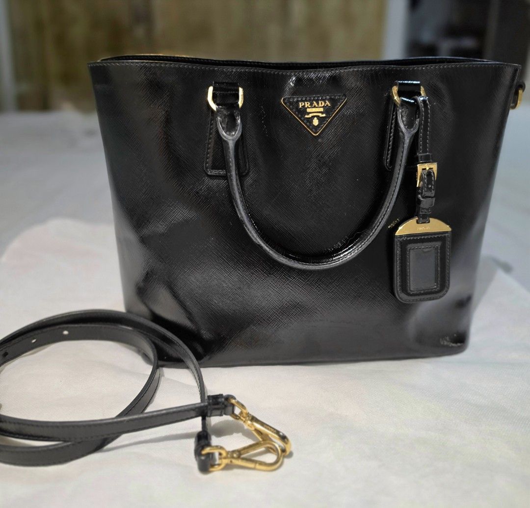 Prada Saffiano Vernice Tote Bag (Category: Luxury Bags & Wallets) located in Paranaque City. Submitted by decluttering_by_anna (Listing ID 1469088091, Image 1). Description: - Authentic Prada tote bag in classic black Saffiano leather - Elegant gold-tone hardware and iconic Prada triangle logo plaque - Dual top handles plus a convenient detachable shoulder strap - Protective metal feet on the bottom base to prevent scuffs - Clean, spacious interi