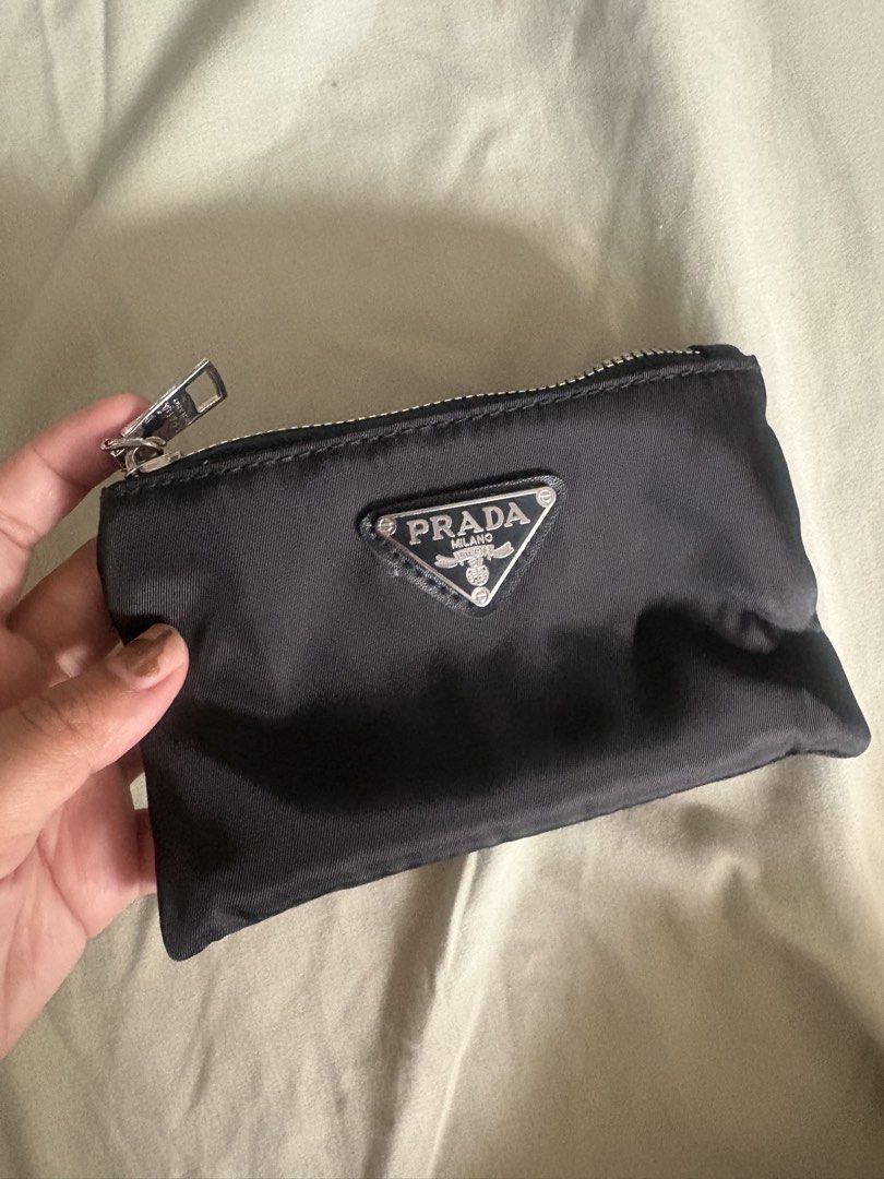 Prada Wallet (Category: Purses & Pouches) located in Manila. Submitted by mndoxajc (Listing ID 1469158449, Image 1). Description: Black nylon pouch by Prada. Silver-tone hardware, zip closure on top. Triangle enamel logo plaque on the front. Inside has dark lining and a small key ring attached. Compact size, handy for storing coins, cards, or small everyday items in your main bag. Clean inside out..