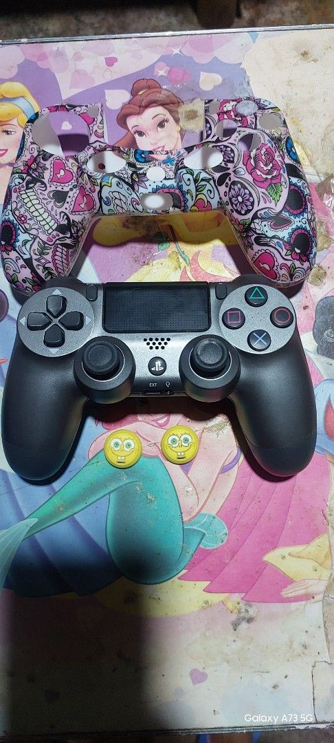 Ps4 controller (Category: Controllers) located in Baras. Submitted by murphy_agnes (Listing ID 1469006247, Image 1). Description: - Authentic PS4 wireless controller in black and grey - Fully functional with responsive buttons and joysticks - Clean overall condition - Includes a vibrant sugar skull silicone case cover - Comes with 2 fun SpongeBob thumb stick grips.