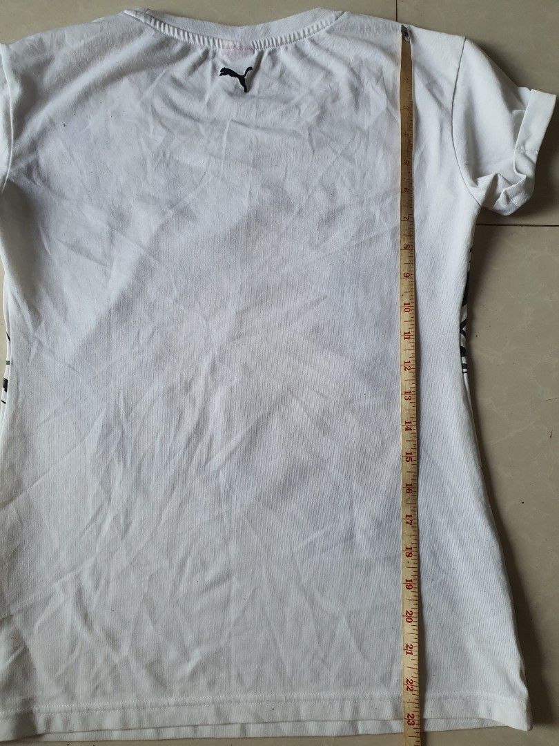 Puma White Black Graphic T-shirt (Category: Shirts) located in Meycauayan. Submitted by shoptoown (Listing ID 1468935900, Image 3). Description: - Brand: Puma - Color: White with large black graphic print on front - Details: Round neckline, short sleeves, small logo tag near hem, and small logo on back collar - Measurements: Approx. 23 inches across (pit-to-pit) and 17 inches in length - Condition: Minor fabric pilling on the white material.