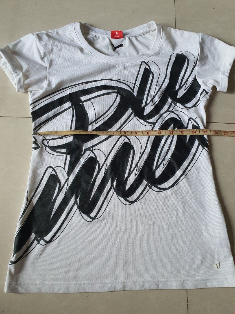 Puma White Black Graphic T-shirt (Category: Shirts) located in Meycauayan. Submitted by shoptoown (Listing ID 1468935900, Image 2). Description: - Brand: Puma - Color: White with large black graphic print on front - Details: Round neckline, short sleeves, small logo tag near hem, and small logo on back collar - Measurements: Approx. 23 inches across (pit-to-pit) and 17 inches in length - Condition: Minor fabric pilling on the white material.