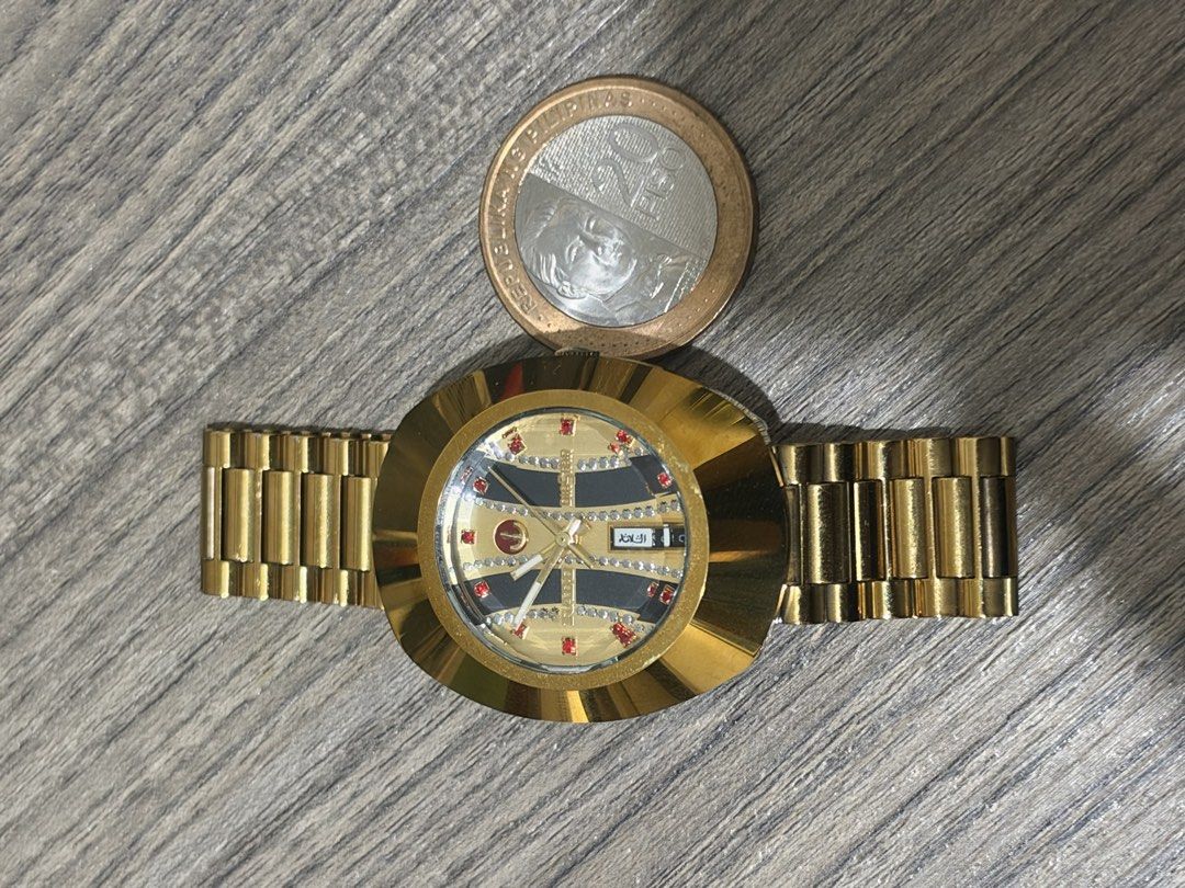 Rado Diastar Gold Watch with Gemstone Dial (Category: Women's Watches) located in Marikina City. Submitted by _julianpaolo (Listing ID 1468937653, Image 3). Description: - Authentic Vintage Rado Diastar gold-tone watch - Oval-shaped case with a striking vertical striped dial - Sparkling stone markers and eye-catching red accent gems - Convenient day and date display at the top - Matching gold link bracelet with original signed Rado clasp - Automa