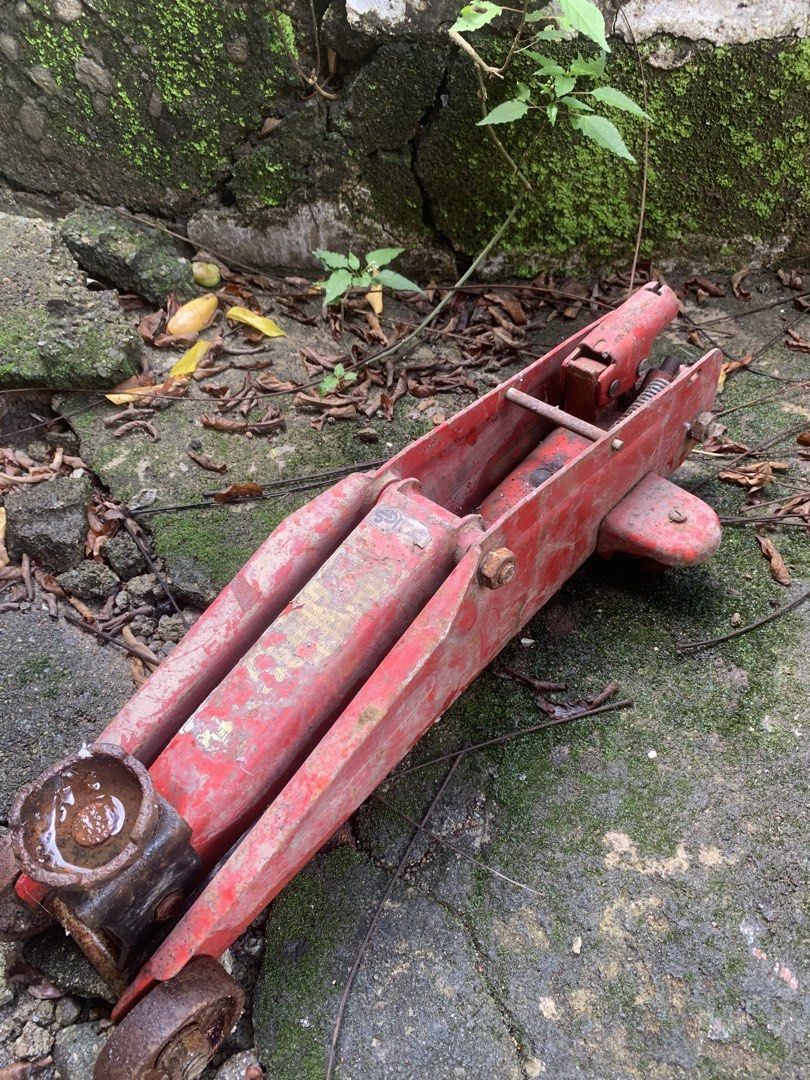 Red Hydraulic Floor Jack (Category: Construction Tools & Equipment) located in Quezon City. Submitted by sojisup (Listing ID 1468985278, Image 2). Description: - Heavy-duty metal red hydraulic floor jack - Wheels still turn smoothly - Significant rust and paint wear due to outdoor storage - Hydraulic mechanism needs testing or servicing - Ideal practical tool for garage work or restoration projects.