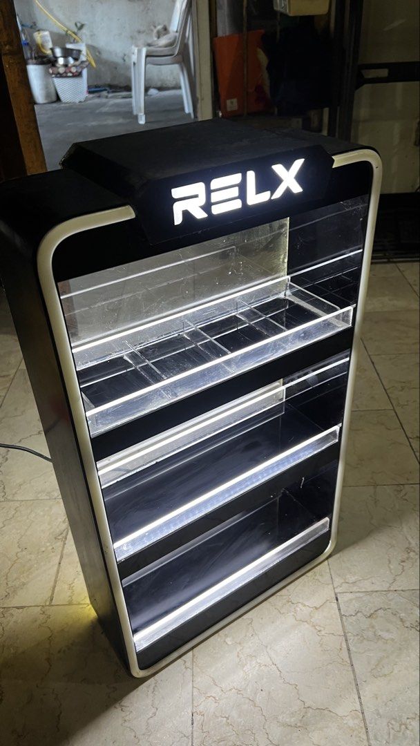 RELX Lighted Display Stand Cabinet (Category: Shelves, Cabinets & Racks) located in Pasig City. Submitted by galgadowt (Listing ID 1469012591, Image 3). Description: Came from the company itself. Bought for P6k Selling for P2,990 last price Good display for business. Or for collectors Brand: RELX - Type: Illuminated display shelf for vapes and accessories - Design: Black frame with LED lighting on outer edges and tiers - Features: Clear acrylic f
