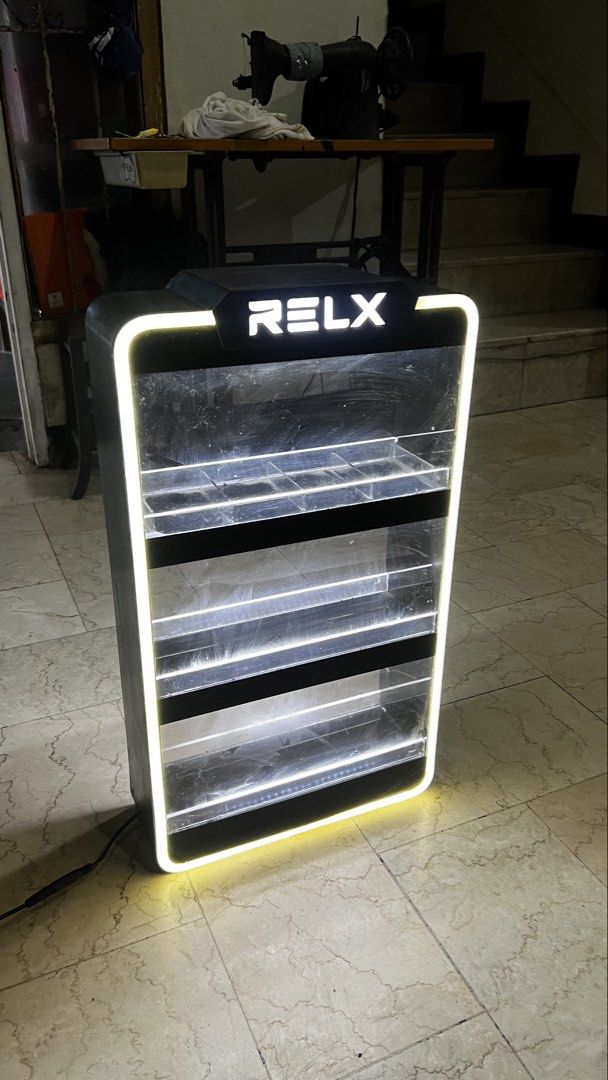 RELX Lighted Display Stand Cabinet (Category: Shelves, Cabinets & Racks) located in Pasig City. Submitted by galgadowt (Listing ID 1469012591, Image 1). Description: Came from the company itself. Bought for P6k Selling for P2,990 last price Good display for business. Or for collectors Brand: RELX - Type: Illuminated display shelf for vapes and accessories - Design: Black frame with LED lighting on outer edges and tiers - Features: Clear acrylic f