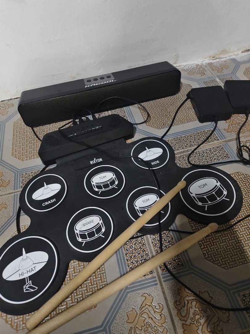 Rixton Portable Electronic Drum Pad Set With Speaker And Pedals (Category: Musical Instruments) located in General Mariano Alvarez. Submitted by findsandmoreph (Listing ID 1469031880, Image 2). Description: - Brand: Rixton Portable Electronic Drum Pad - Complete bundle includes: Roll-up silicone pad, Kacool black soundbar speaker, 2 foot pedals (bass & -hat), and wooden drum sticks - Features multiple percussion zones: snare, -hat, crash, ride, a