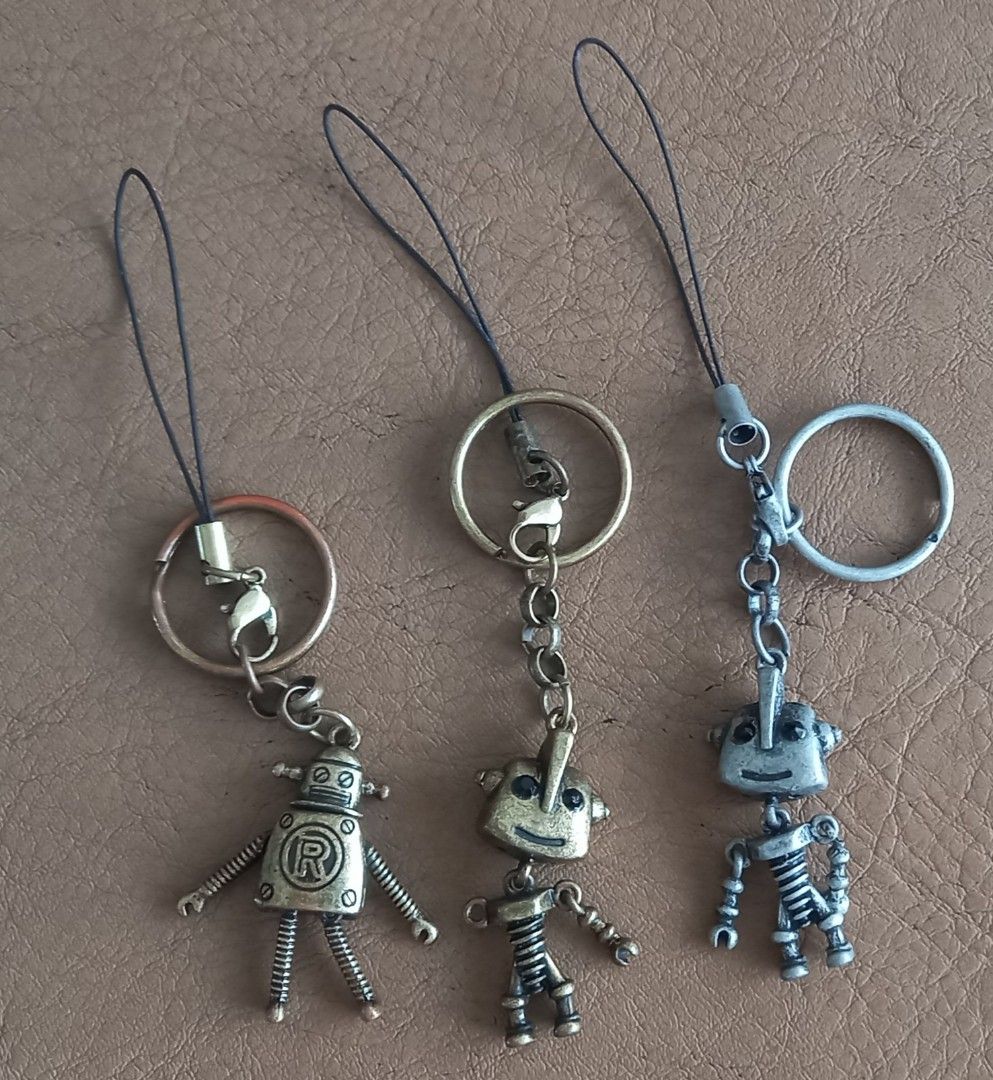 Robot Keychain Phone Charm Set of Three (Category: Character Goods) located in Cagayan de Oro. Submitted by edwardryan01984 (Listing ID 1468933357, Image 1). Description: - Set of 3 robot keychains (2 bronze, 1 silver) - Features phone straps and metal key rings - Flexible spring arms and legs that move - Fun accessory for keys, bags, or mobile phones - Selling as a bundle set only.