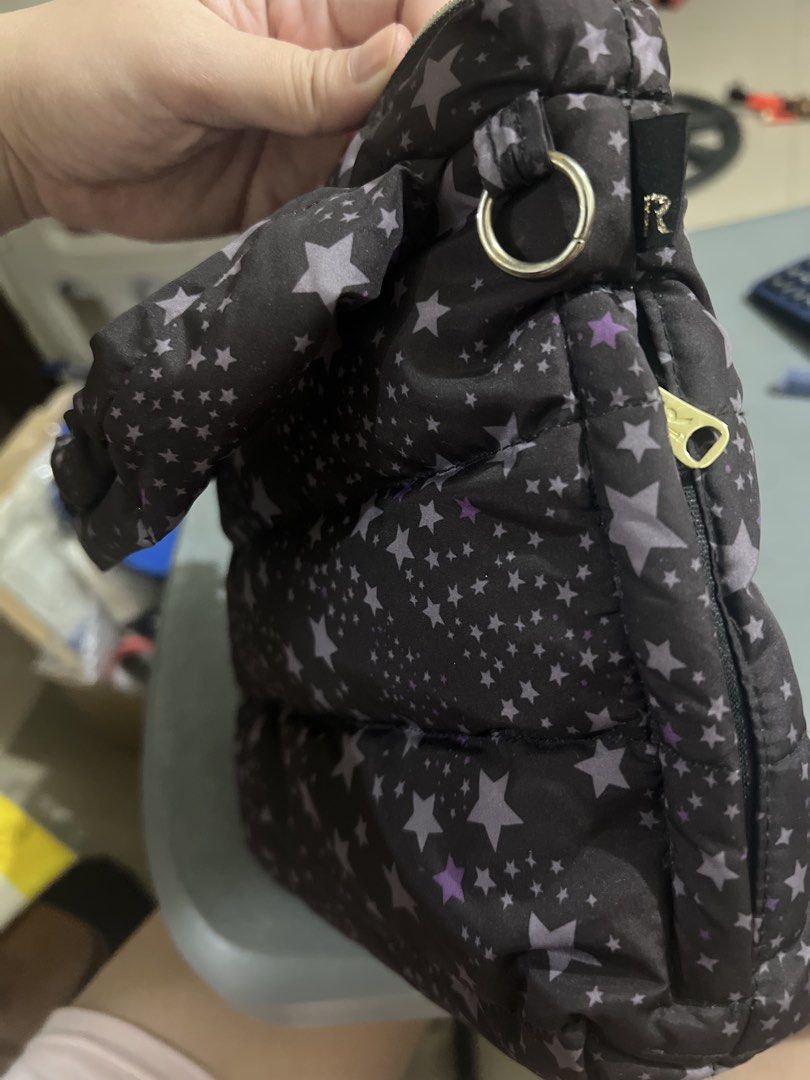 Rootote Star Print Puffer Tote Handbag (Category: Tote Bags) located in Manila. Submitted by ajdfinds (Listing ID 1469092041, Image 3). Description: - Brand: Rootote - Color/Pattern: Black with grey and purple star print - Material: Puffy quilted fabric - Closure: Zippered with branded silver pull tab - Interior: Grey lining with slip pockets and brand tags - Features: Lightweight, roomy, and versatile for everyday use -Top handle use only / No s