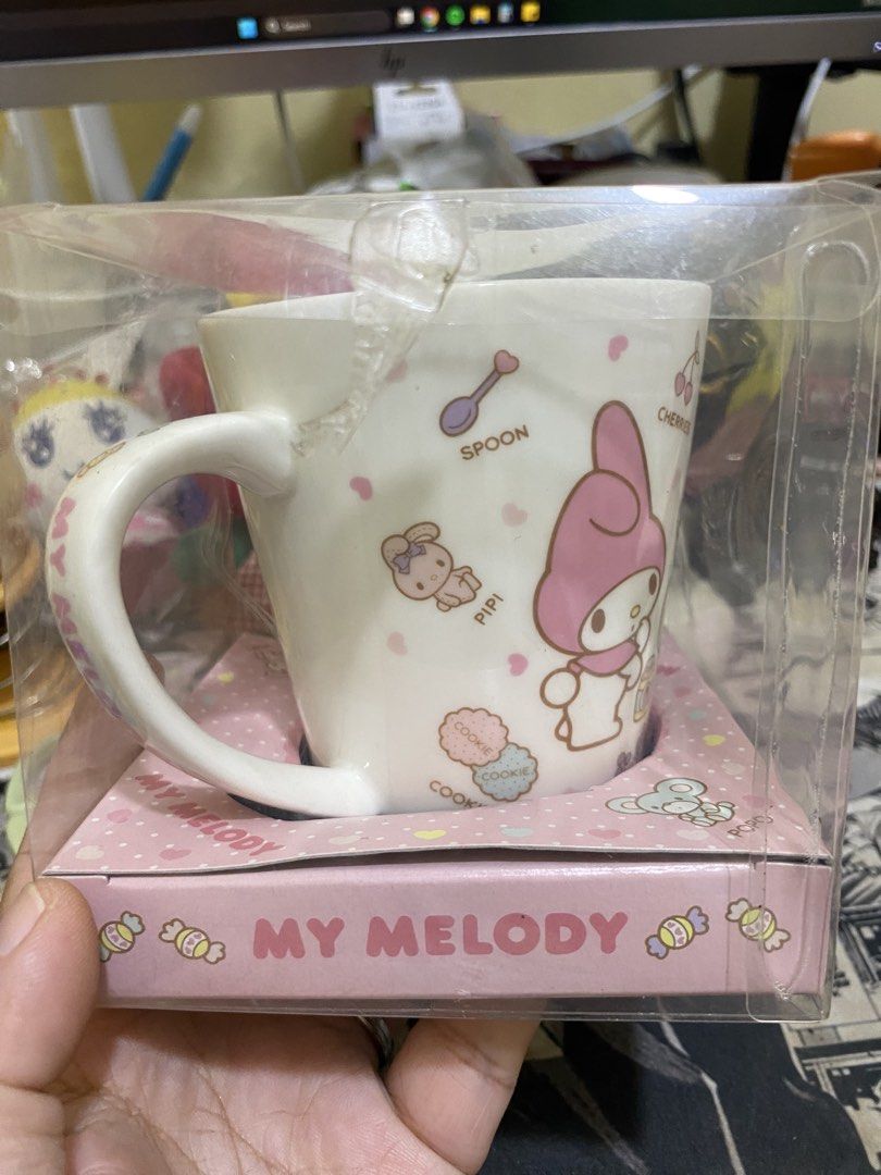 Sanrio My Melody Ceramic Mug (Category: Coffee & Tea Tableware) located in Imus. Submitted by mnmv23 (Listing ID 1468996258, Image 2). Description: - Vintage 2012 Sanrio My Melody collectible mug - Premium white ceramic mug made in Japan - Features cute designs of My Melody, Popo, Pipi, apples, and donuts - Comes in original clear packaging with a pink polka dot box base - Includes original commemorative cookies (Expired March 2013, FOR DISPLAY O