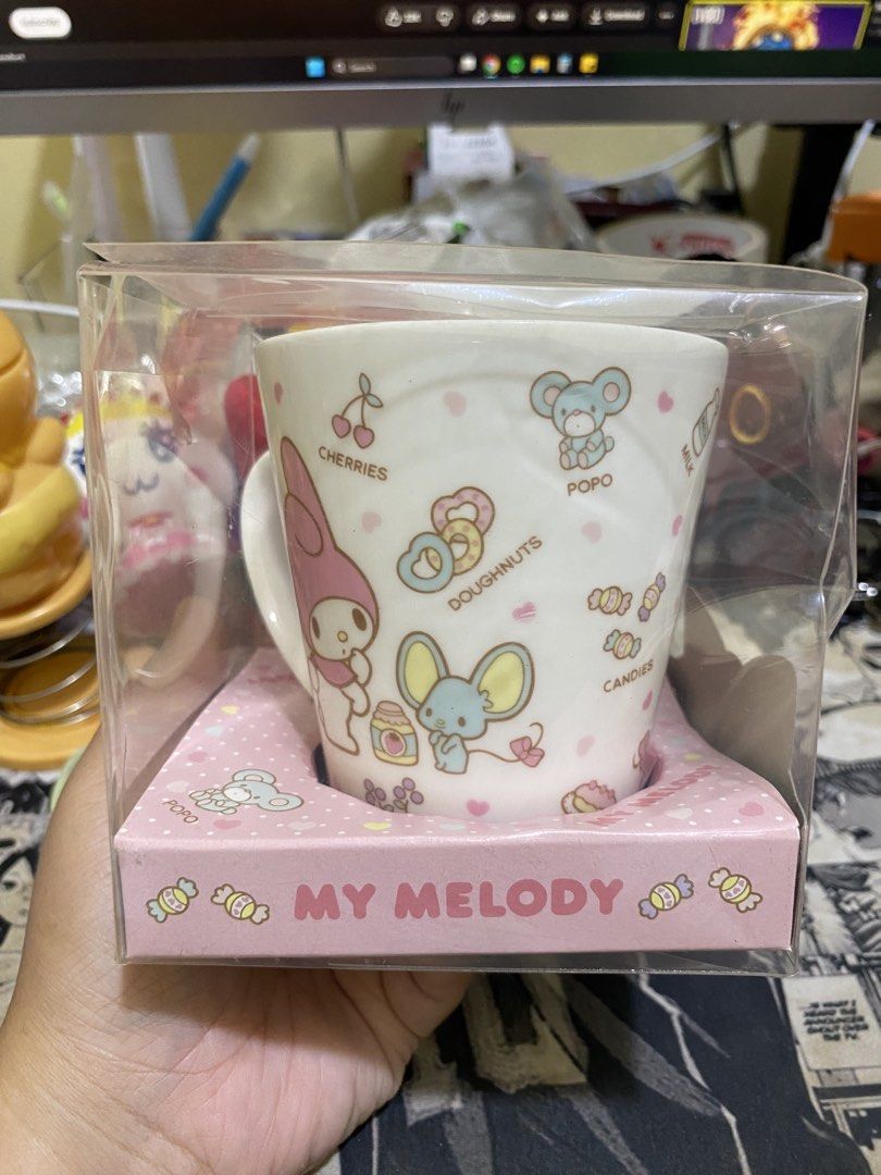 Sanrio My Melody Ceramic Mug (Category: Coffee & Tea Tableware) located in Imus. Submitted by mnmv23 (Listing ID 1468996258, Image 1). Description: - Vintage 2012 Sanrio My Melody collectible mug - Premium white ceramic mug made in Japan - Features cute designs of My Melody, Popo, Pipi, apples, and donuts - Comes in original clear packaging with a pink polka dot box base - Includes original commemorative cookies (Expired March 2013, FOR DISPLAY O