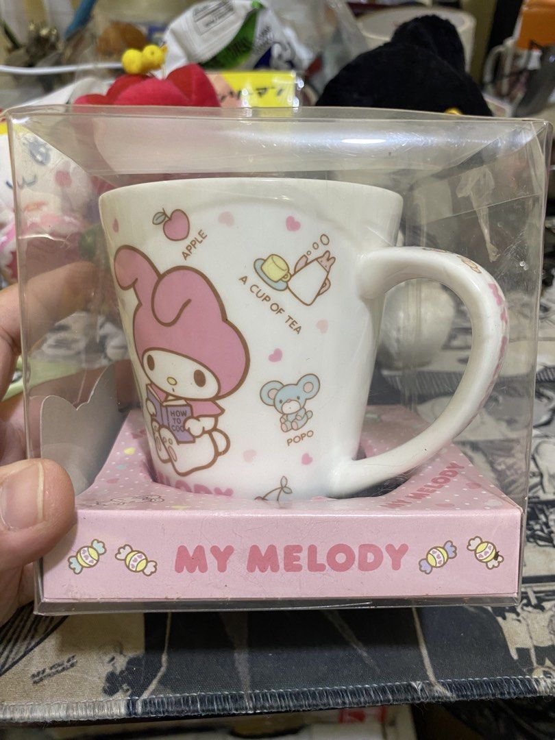 Sanrio My Melody Ceramic Mug (Category: Coffee & Tea Tableware) located in Imus. Submitted by mnmv23 (Listing ID 1468996258, Image 3). Description: - Vintage 2012 Sanrio My Melody collectible mug - Premium white ceramic mug made in Japan - Features cute designs of My Melody, Popo, Pipi, apples, and donuts - Comes in original clear packaging with a pink polka dot box base - Includes original commemorative cookies (Expired March 2013, FOR DISPLAY O
