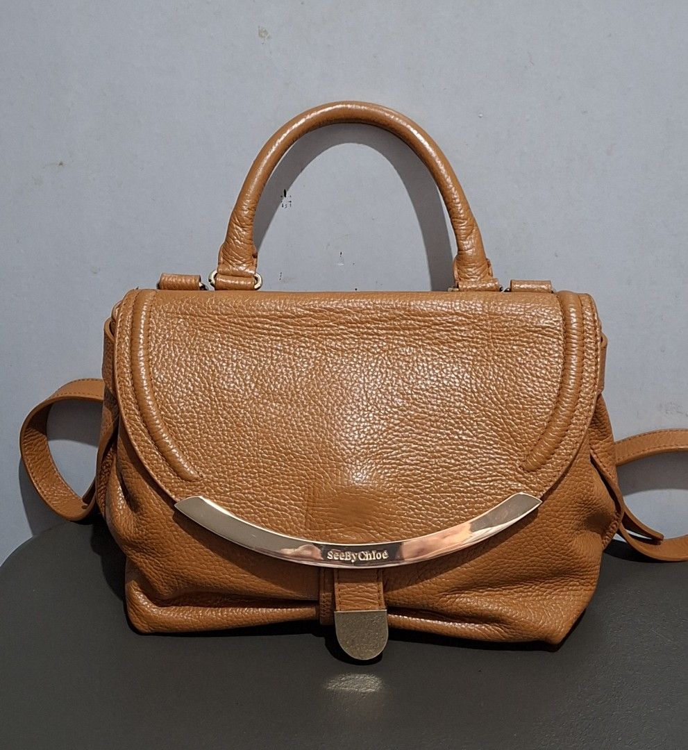 See By Chloe Tan Leather Shoulder Bag (Category: Luxury Bags & Wallets) located in Quezon City. Submitted by moonthrifting (Listing ID 1468939889, Image 1). Description: - Authentic See By Chloe shoulder bag in gorgeous tan pebbled leather - Eye-catching curved metal hardware plate with embossed branding on the front flap - Versatile carry options: structured top handle and adjustable/removable leather strap with gold-tone clips - Secure main fla