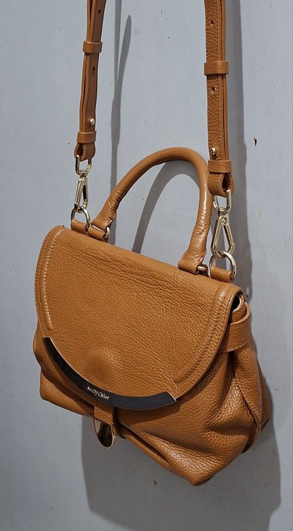See By Chloe Tan Leather Shoulder Bag (Category: Luxury Bags & Wallets) located in Quezon City. Submitted by moonthrifting (Listing ID 1468939889, Image 2). Description: - Authentic See By Chloe shoulder bag in gorgeous tan pebbled leather - Eye-catching curved metal hardware plate with embossed branding on the front flap - Versatile carry options: structured top handle and adjustable/removable leather strap with gold-tone clips - Secure main fla
