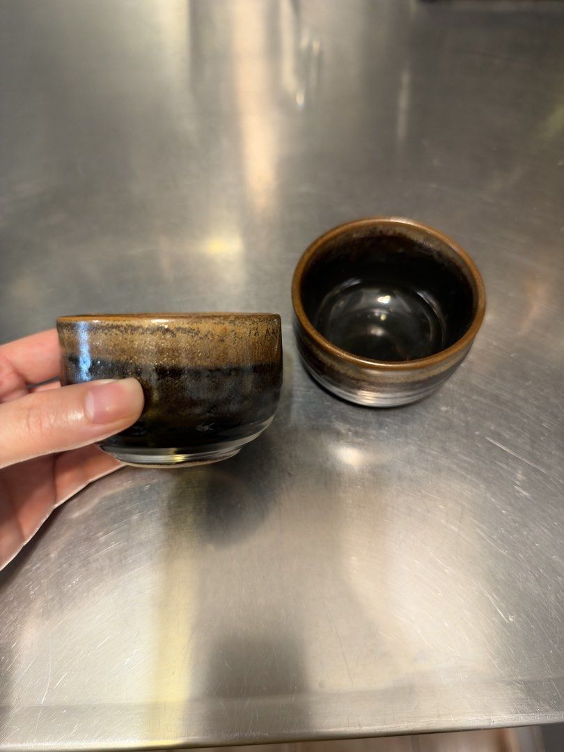 Set of Two Ceramic Tea Cups (Category: Coffee & Tea Tableware) located in Manila. Submitted by garagesalebykoda (Listing ID 1468987762, Image 2). Description: - Set of 2 small ceramic cups - Dark brown and black glaze with glossy interior - Handmade-style texture along the rim and body - Ideal size for tea or sake - Condition: Excellent, clean insides with no cracks or chips.