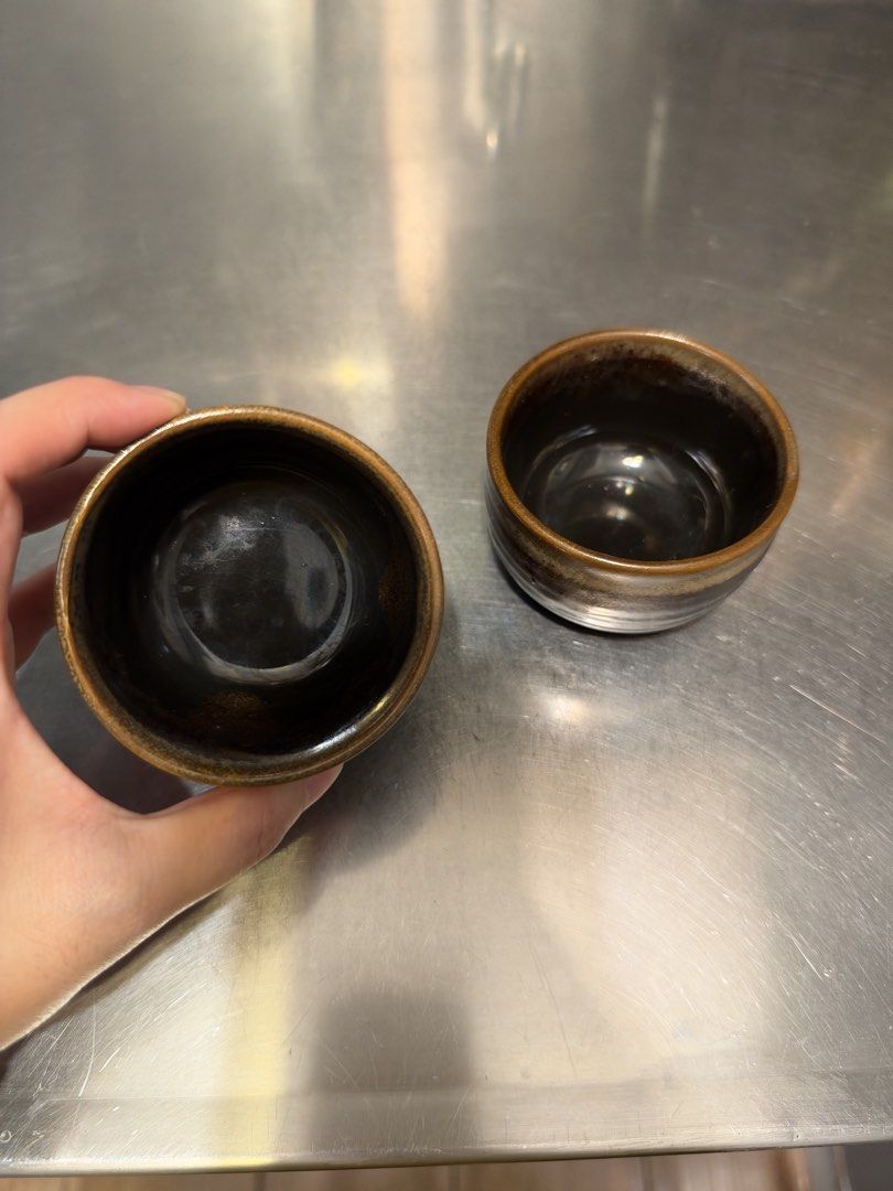 Set of Two Ceramic Tea Cups (Category: Coffee & Tea Tableware) located in Manila. Submitted by garagesalebykoda (Listing ID 1468987762, Image 3). Description: - Set of 2 small ceramic cups - Dark brown and black glaze with glossy interior - Handmade-style texture along the rim and body - Ideal size for tea or sake - Condition: Excellent, clean insides with no cracks or chips.