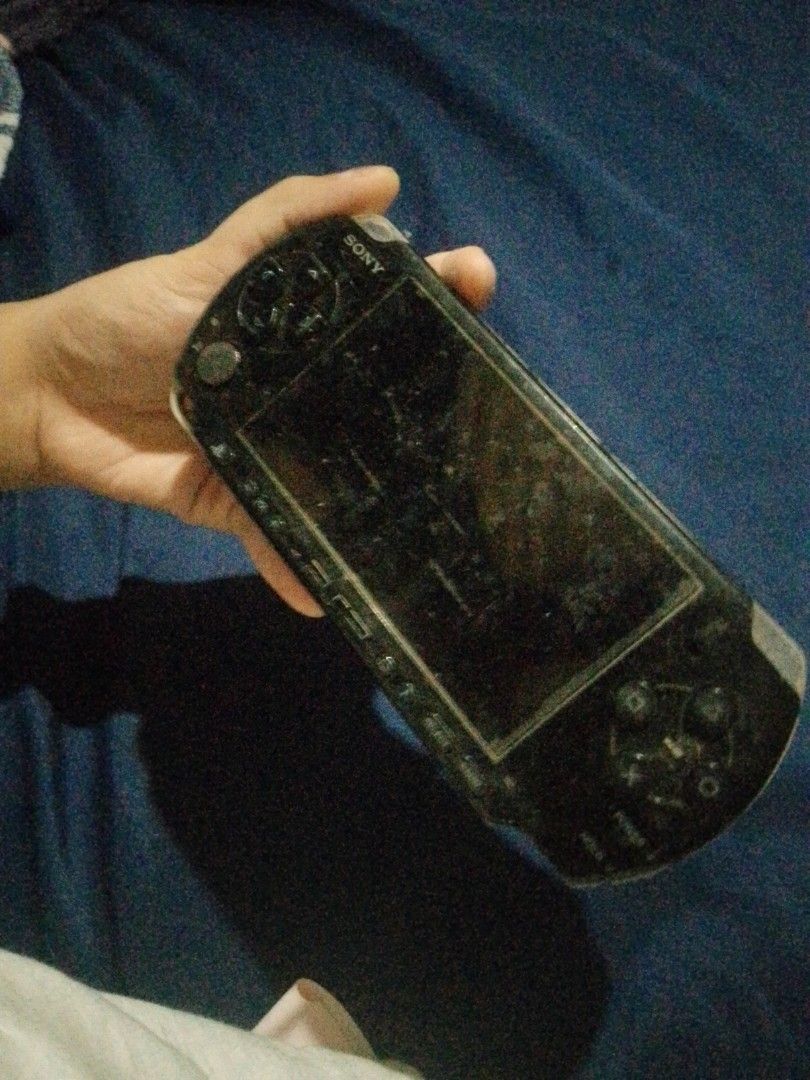 Sony PSP Handheld Console (Category: PlayStation) located in Quezon City. Submitted by mahiwagangkamote (Listing ID 1469023396, Image 1). Description: - Item: Black Sony portable gaming console - Condition: Heavy wear, dirt accumulation, and rust near the charging port - Screen: Numerous scratches and dust present - Battery: Cover is missing, battery is exposed - Purpose: Selling strictly as-is for spare parts or a restoration project - Note: Req