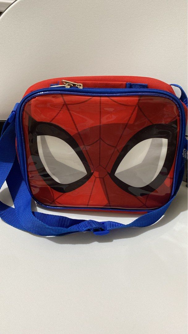 Spider-Man Lunch Bag with Strap (Category: Tote Bags) located in Silang. Submitted by princess_jasmin (Listing ID 1469104854, Image 1). Description: - Official Spider-Man design featuring a bold red and blue glossy mask on the front - Insulated interior to keep meals and snacks fresh all day - Secure top zipper closure for easy access - Comfortable, adjustable blue shoulder strap for carrying convenience - Roomy compartment ideal for school lunch