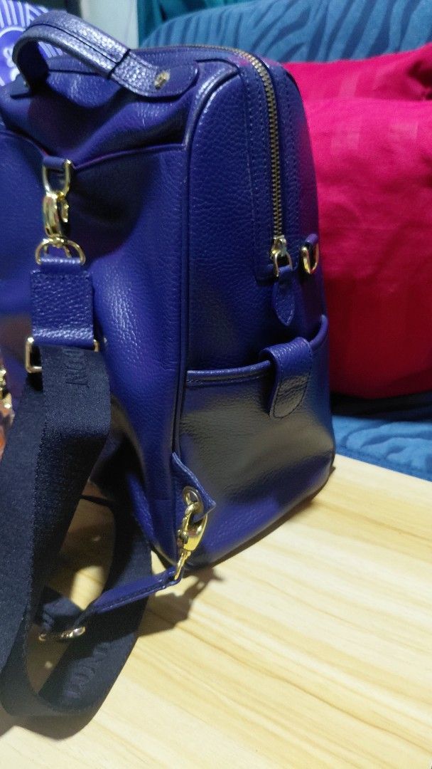 St. Scott London Blue Leather Backpack (Category: Backpacks) located in Davao. Submitted by floresjayne0124 (Listing ID 1468939768, Image 3). Description: - Brand: St. Scott London - Material: Blue pebbled leather with gold hardware - Interior: Pink patterned fabric lining with multiple compartments - Pockets: Front zipper pocket and side pocket flap - Straps: Adjustable black straps with branded lettering plus top handle - Condition: Clean insid
