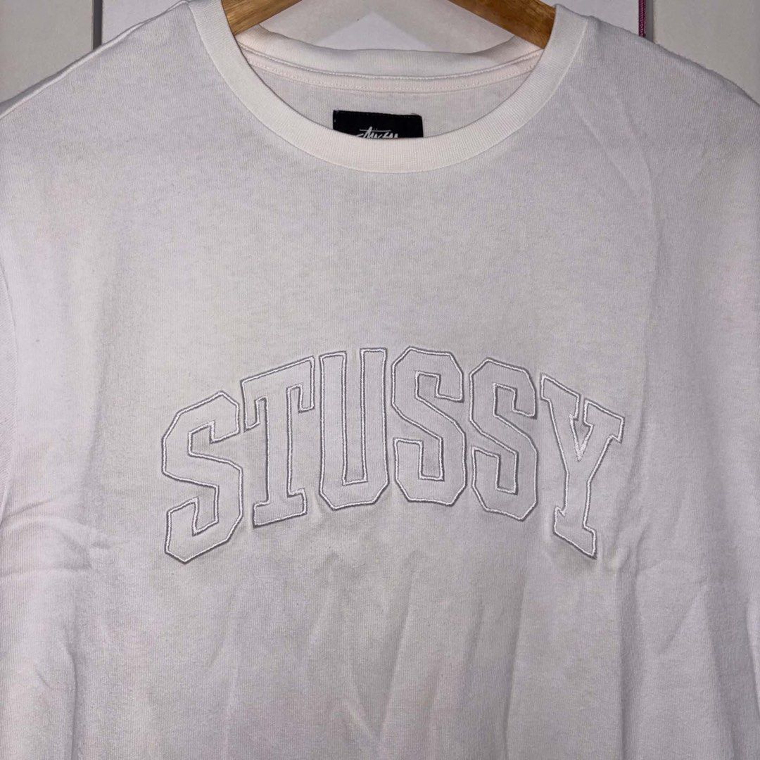 Stussy Arch Logo White Tee (Category: Tshirts & Polo Shirts ) located in Rosario. Submitted by elyukano2506 (Listing ID 1469019300, Image 2). Description: - Brand: Stussy - Item: Short sleeve t-shirt - Color: White with white outline embroidered collegiate logo - Size: Small fit to Medium -width 21 -length 27.5 - Fit: Regular fit, clean cotton fabric - Details: Crew neck with black branded neck tag - Condition: Great streetwear staple, ready for 