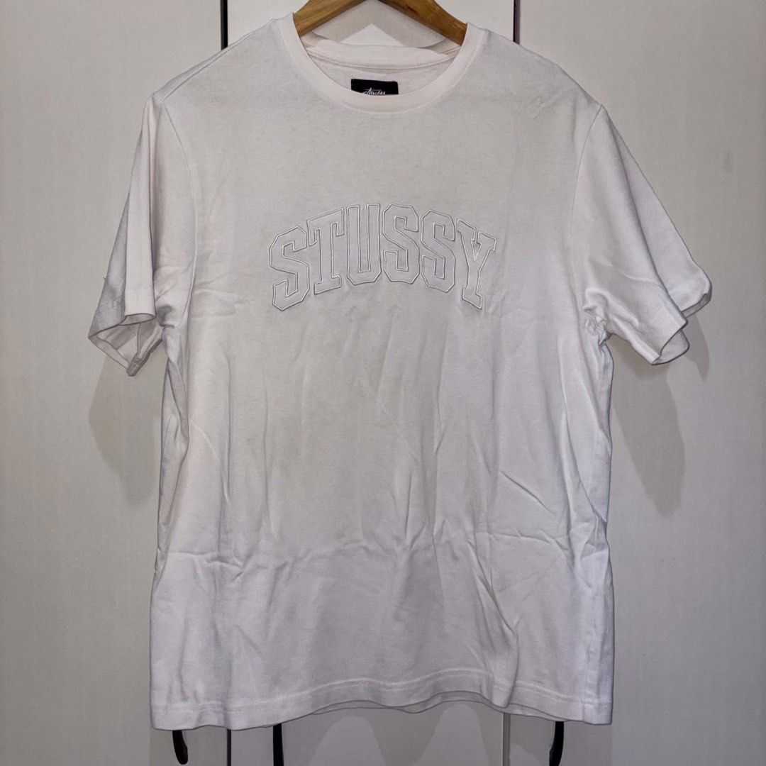 Stussy Arch Logo White Tee (Category: Tshirts & Polo Shirts ) located in Rosario. Submitted by elyukano2506 (Listing ID 1469019300, Image 1). Description: - Brand: Stussy - Item: Short sleeve t-shirt - Color: White with white outline embroidered collegiate logo - Size: Small fit to Medium -width 21 -length 27.5 - Fit: Regular fit, clean cotton fabric - Details: Crew neck with black branded neck tag - Condition: Great streetwear staple, ready for 