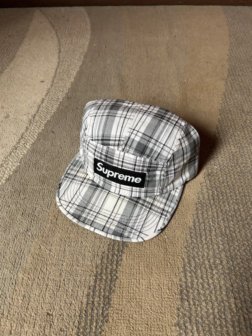 Supreme 2007 Plaid Camp Cap (Category: Caps & Hats) located in Abucay. Submitted by stuttt (Listing ID 1468995225, Image 1). Description: - Authentic Supreme 5-panel camp cap - Black and white plaid pattern with classic box logo patch - Adjustable black nylon strap with plastic buckle closure - Made in U.S.A. with interior tags intact - Note: Shows minor fraying along the interior sweatband seams.
