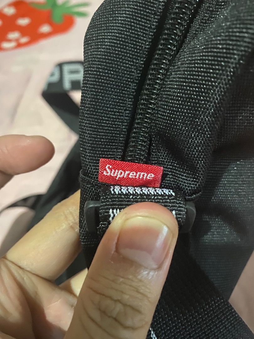 Supreme ss18 Black Shoulder Bag (Category: Sling Bags) located in Mabalacat. Submitted by zesko_ (Listing ID 1468992073, Image 2). Description: Black Supreme shoulder bag with durable canvas material. Red box logo tag stitched near the zipper. Adjustable strap with printed branding. Heavy-duty plastic buckle attached. Clean stitching along the seams and zipper track. Everyday carry size, great for daily use..