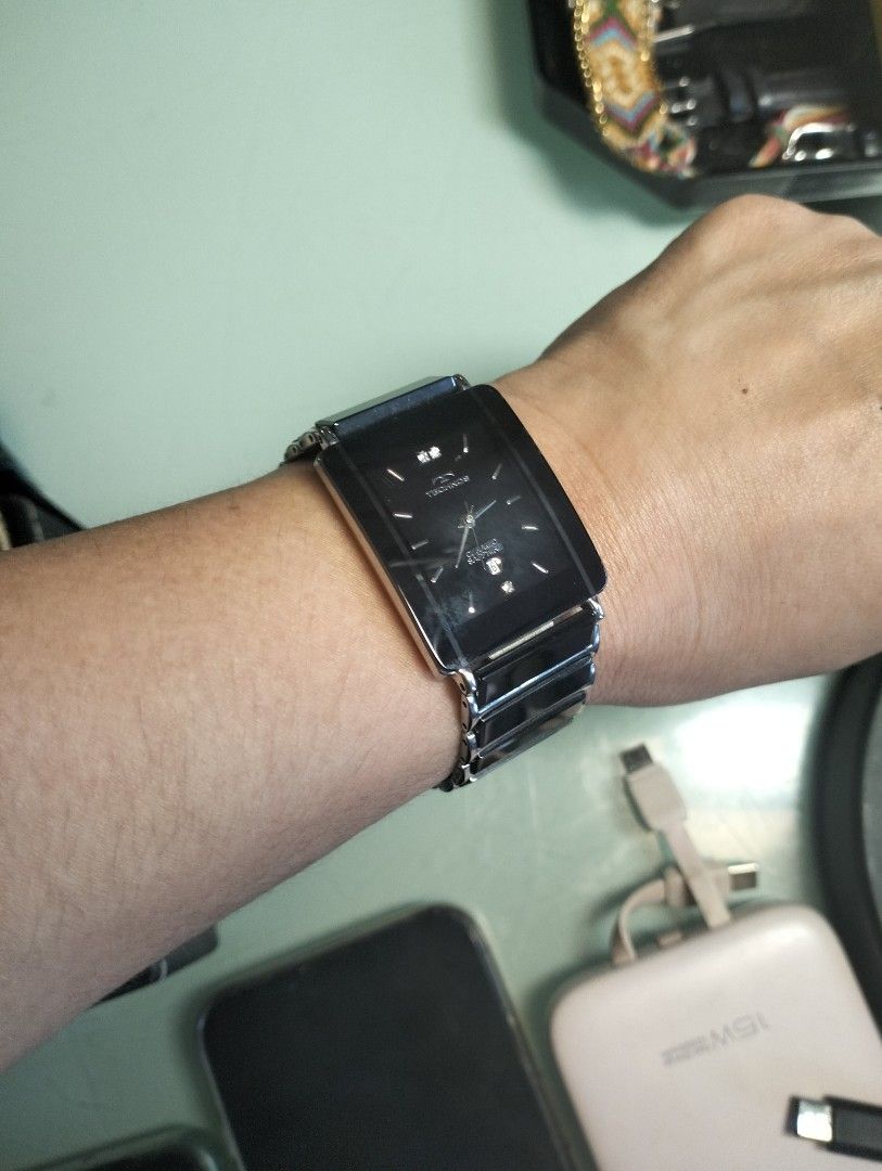 Technos Sapphire Ceramic Quartz Watch Rectangular Black Dial (Category: Men's Watches) located in General Mariano Alvarez. Submitted by ma.miafajardo1219 (Listing ID 1469107741, Image 3). Description: Technos watch with rectangular black dial. Ceramic and stainless steel bracelet links. Sapphire crystal glass face. Date window at the bottom. Small diamond markers at the top and bottom of the dial. Quartz movement. Minimal wear on the links. Stand